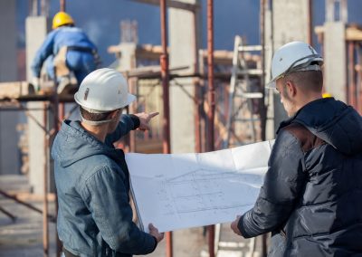 Ingénieurs économistes de la construction examinant un plan d'exécution lors d'une expertise technique à Conflans-Sainte-Honorine.